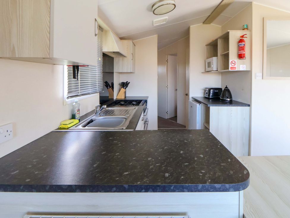 A kitchen with cabinets and appliances at Dunes View in Prestatyn
