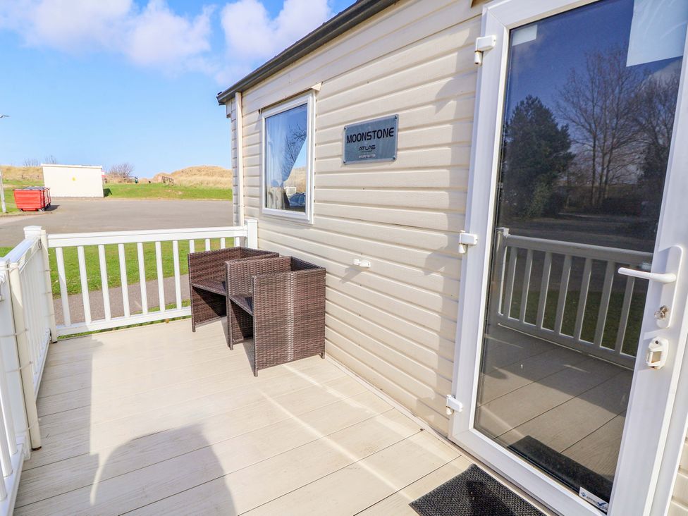 An outdoor area with wicker chairs and a deck at Dunes View in Prestatyn
