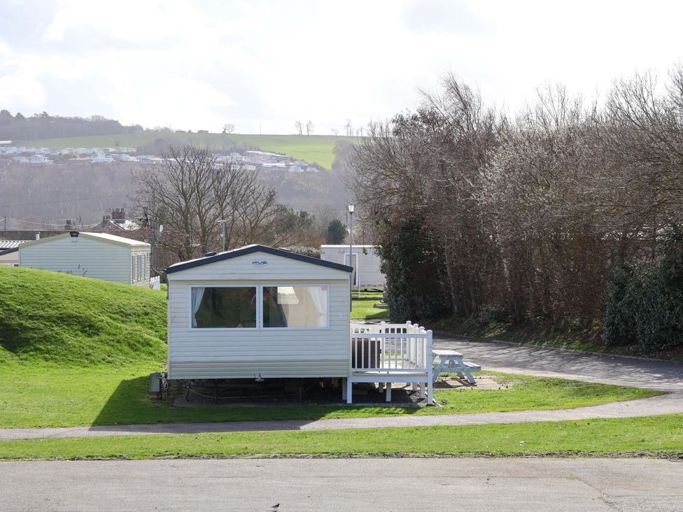 A static caravan with green grass and trees at Dunes View in Prestatyn