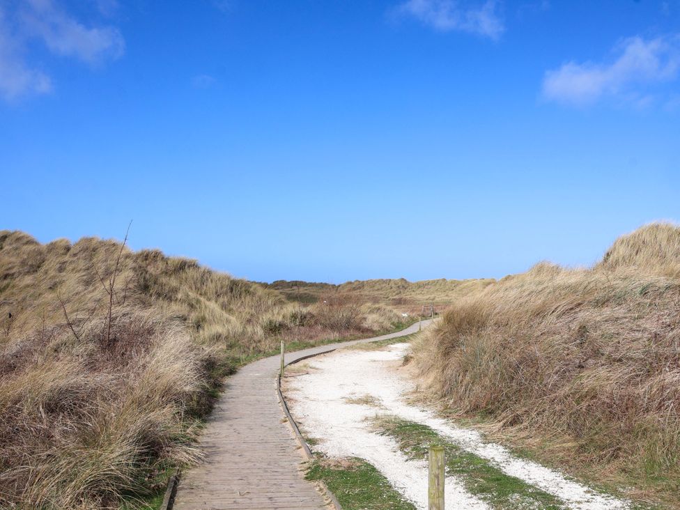 A path through sand dunes under a blue sky at Dunes View in Prestatyn