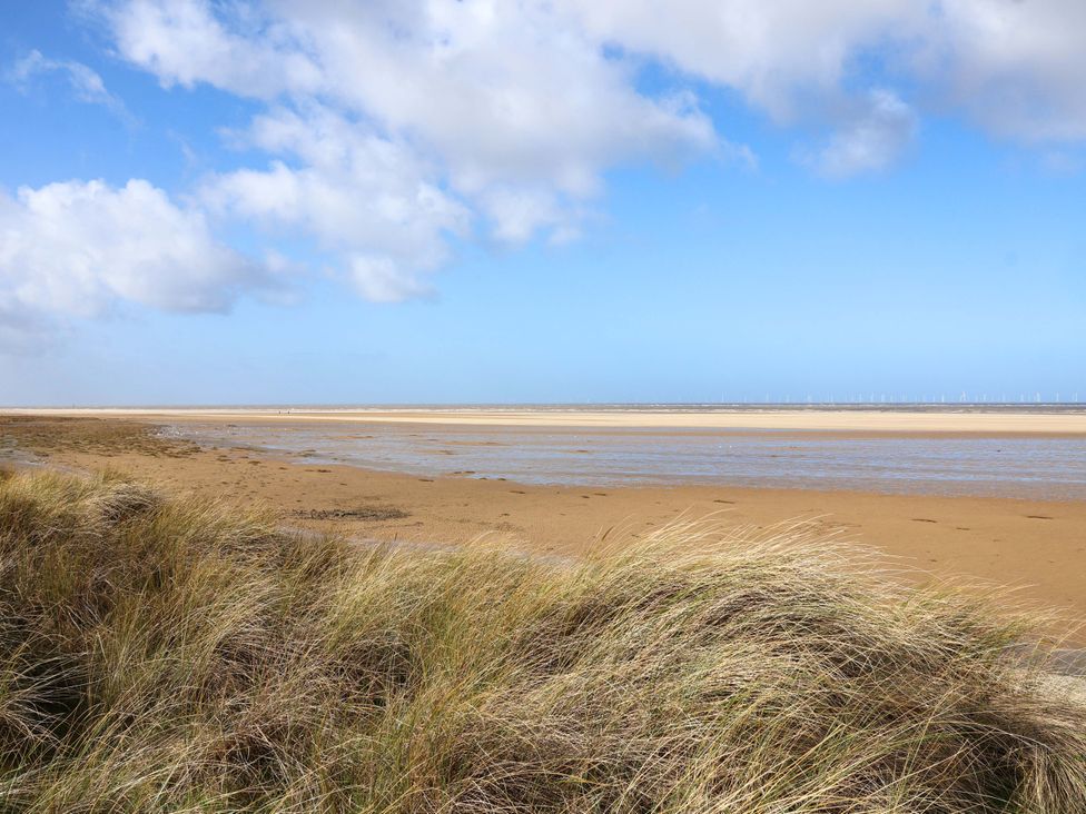 A beach scene with grass and water at Dunes View in Prestatyn