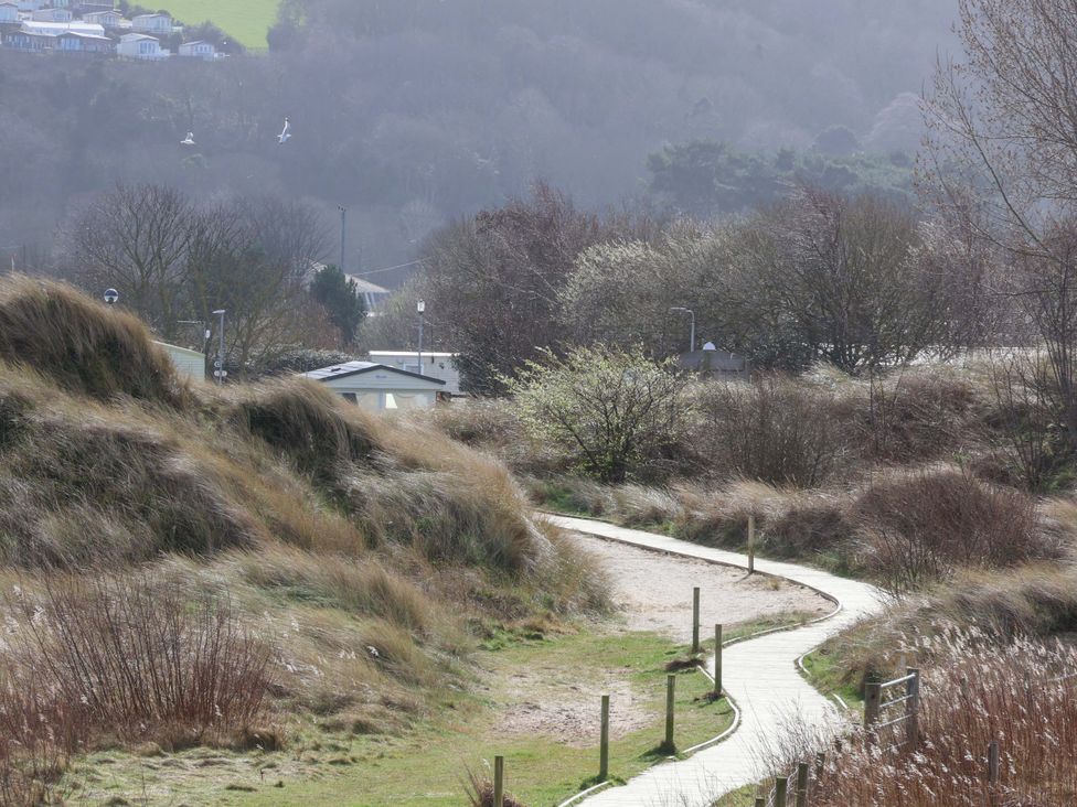 A pathway through dunes with bushes and mobile homes at Dunes View in Prestatyn