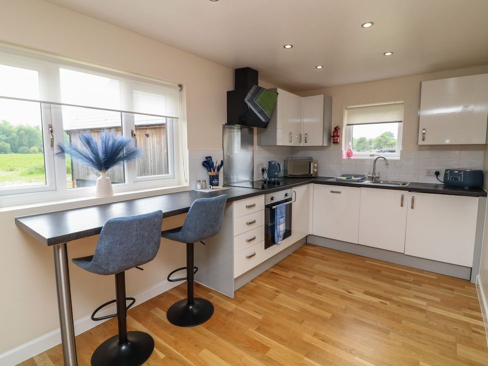 A kitchen with bar stools and kitchen appliances at James Ville Marina Lodge 21 in Brigg