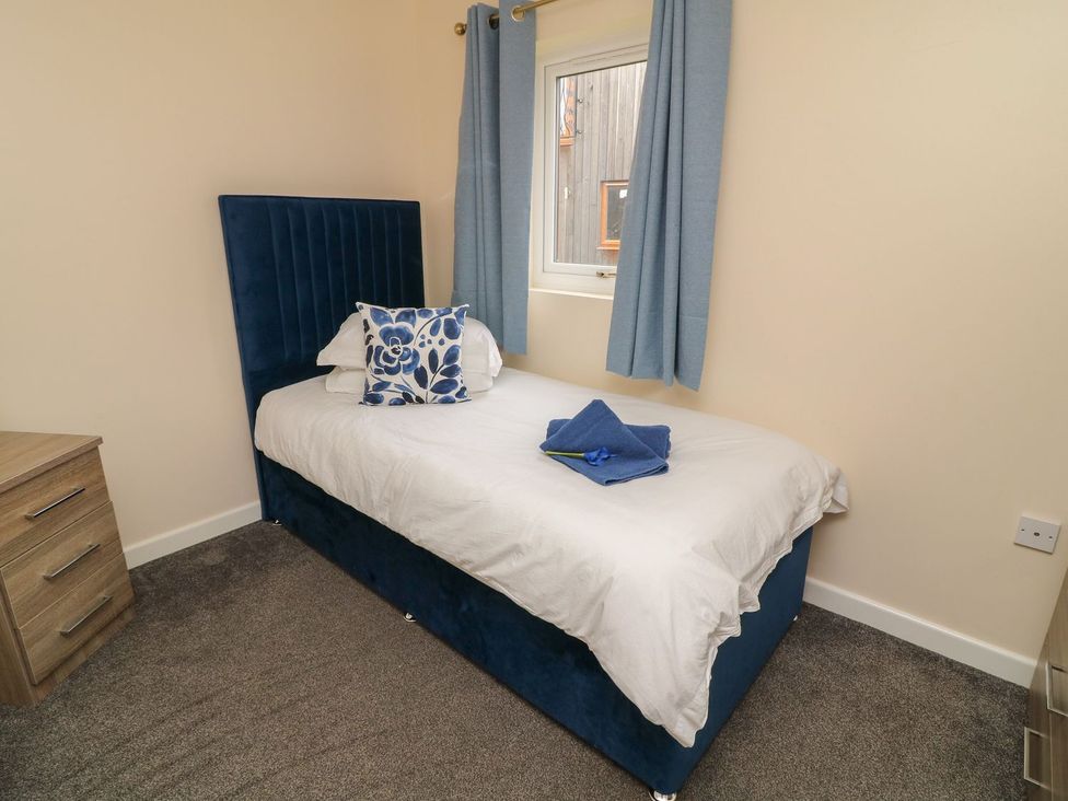 A bedroom with a bed, dresser and window at James Ville Marina Lodge 21 in Brigg