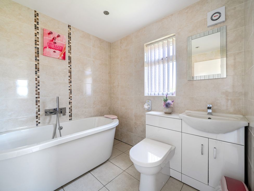 A bathroom with a bathtub, toilet, sink, and window at James Ville Marina Lodge 23 in Brigg