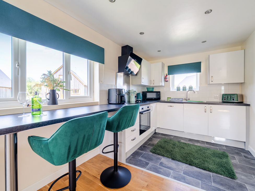 A kitchen with bar stools at James Ville Marina Lodge 22 in Brigg