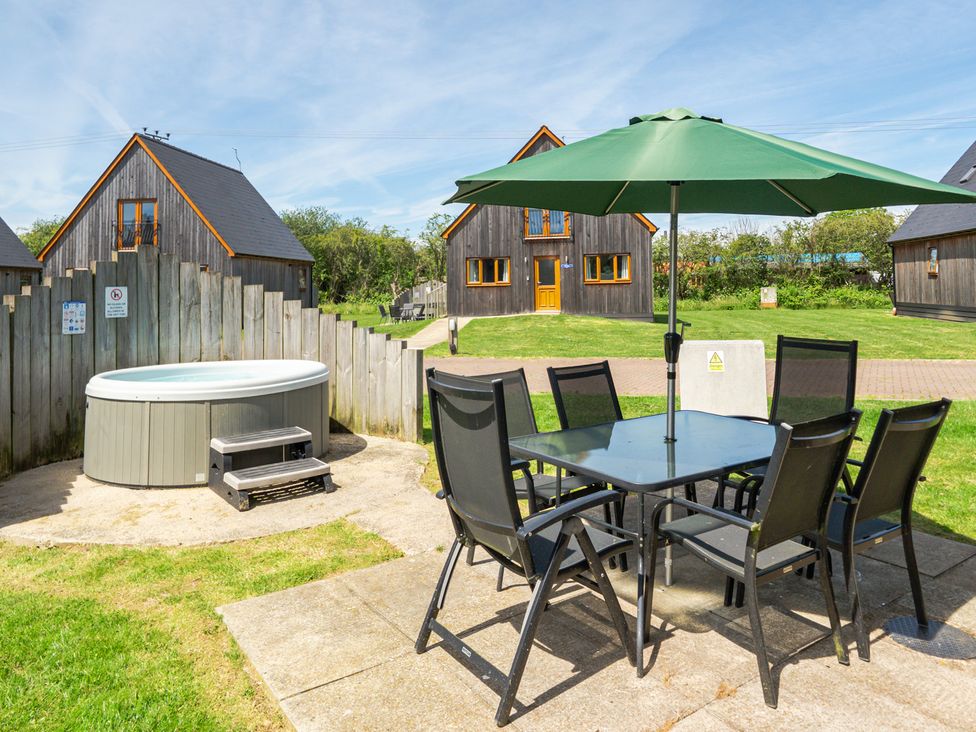An outdoor area with a hot tub and a dining set at James Ville Marina Lodge 22 in Brigg
