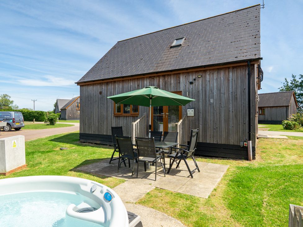 An outdoor area with a house, patio table, and hot tub at James Ville Marina Lodge 22 in Brigg