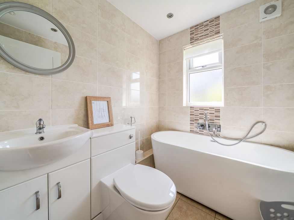 A bathroom with a bathtub, toilet, sink, and mirror at James Ville Marina Lodge 10 in Brigg