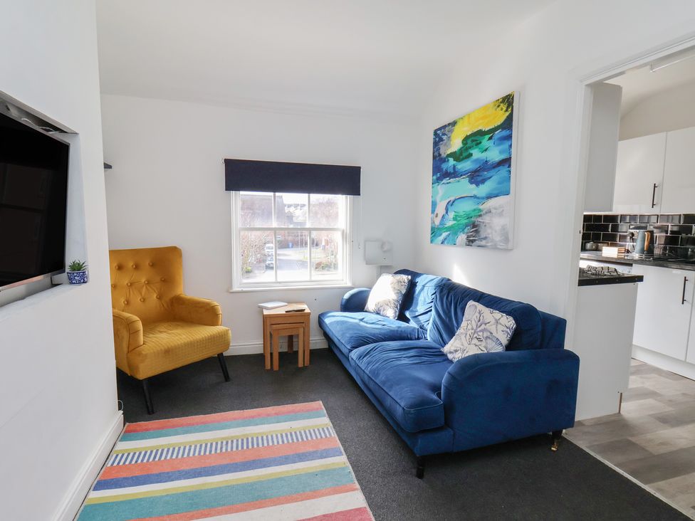 A living room with a blue sofa and yellow armchair at Apartment 3 in Scarborough