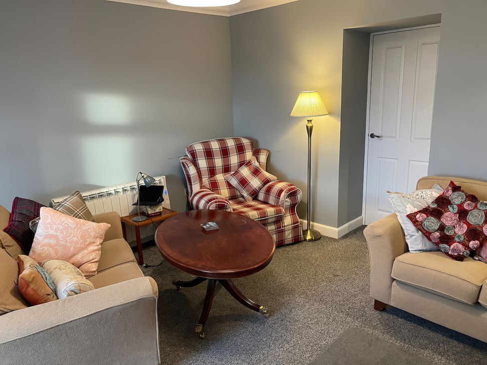 A living room with a table and armchair at 15 New Shawbost in Shawbost