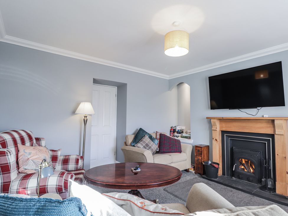 A living room with a fireplace and seating at 15 New Shawbost in Shawbost