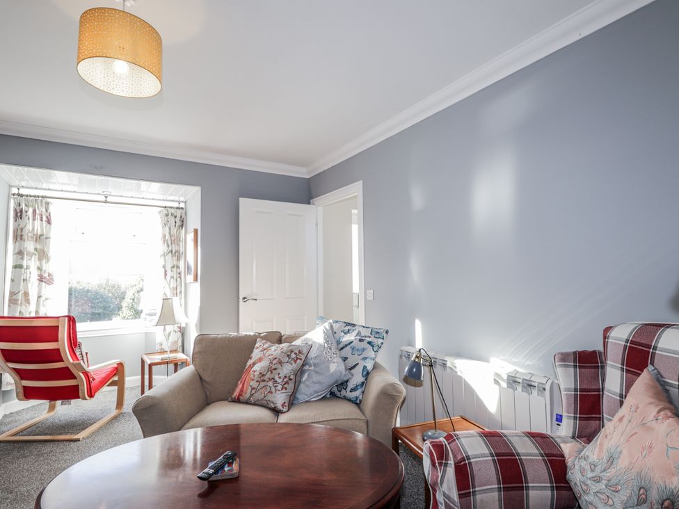 A living room with an armchair and table at 15 New Shawbost in Shawbost