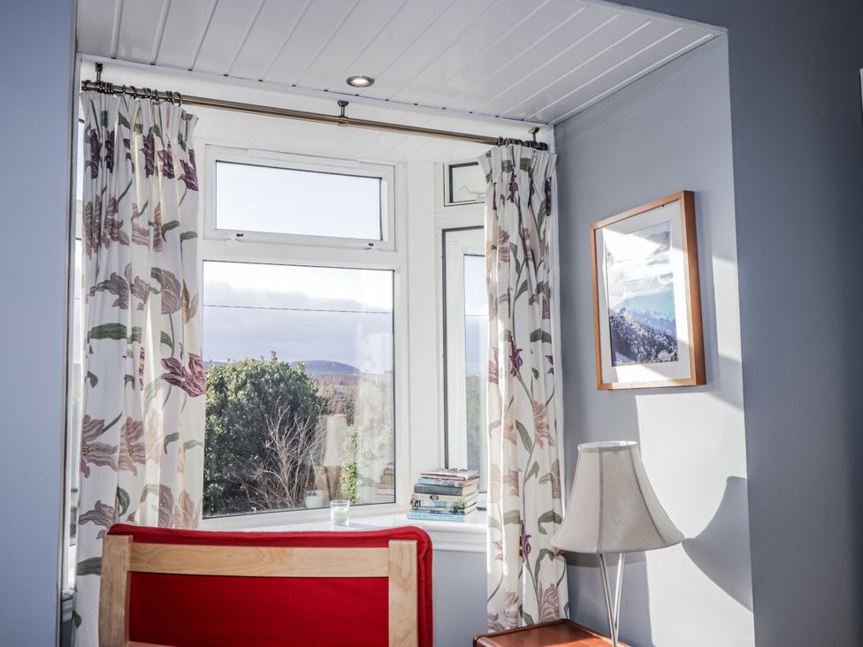 A snug with a window, lamp, and books at 15 New Shawbost in Shawbost