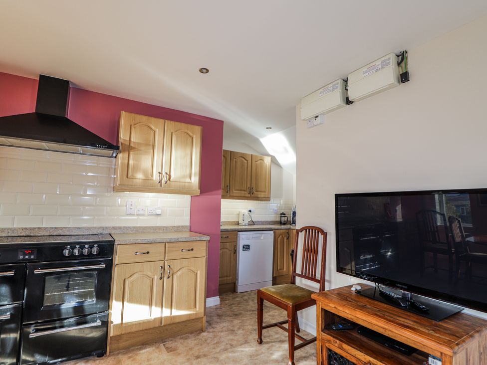 A kitchen with cabinets, oven, fridge, and television at 15 New Shawbost in Shawbost