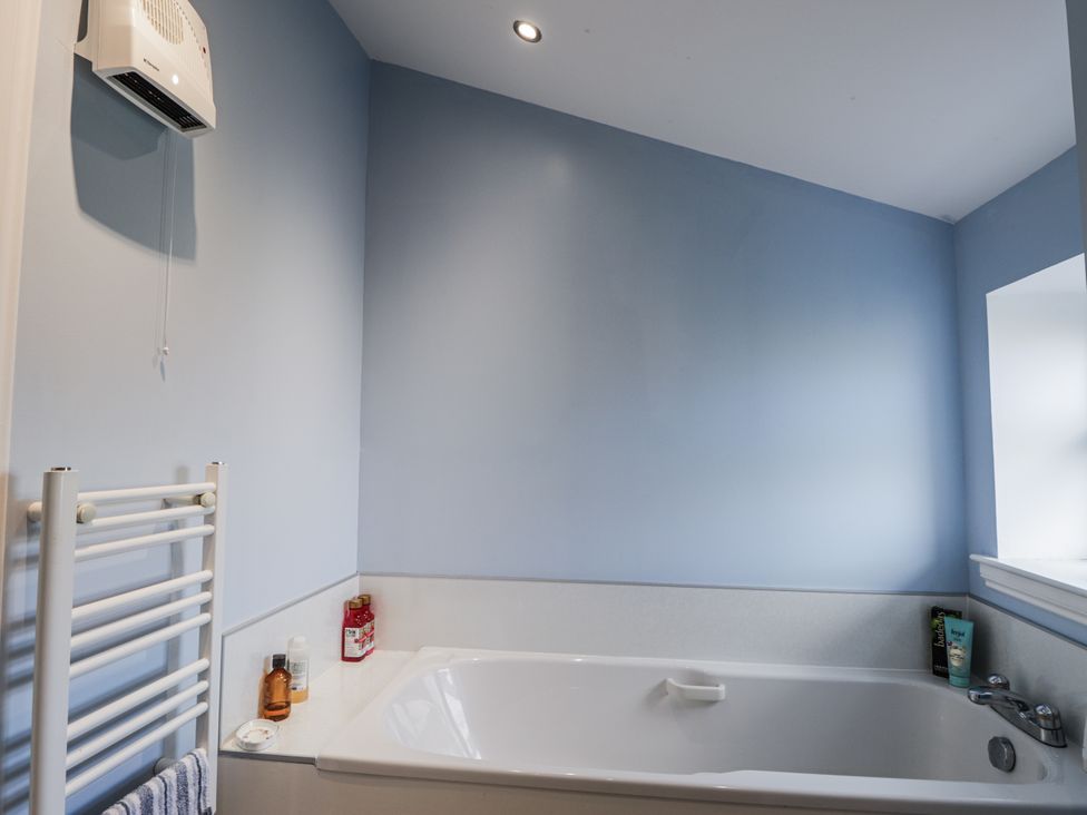 A bathroom with a bathtub and towel rail at 15 New Shawbost in Shawbost