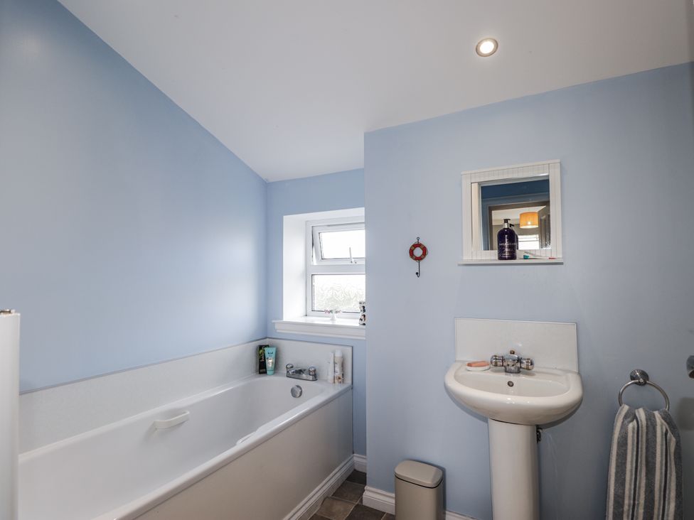 A bathroom with a bathtub, sink, and window at 15 New Shawbost in Shawbost