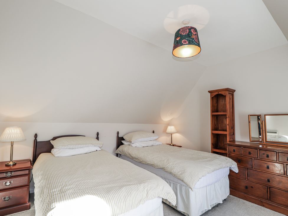 A bedroom with two beds, a lamp, a dresser, and a shelf at 15 New Shawbost, Shawbost