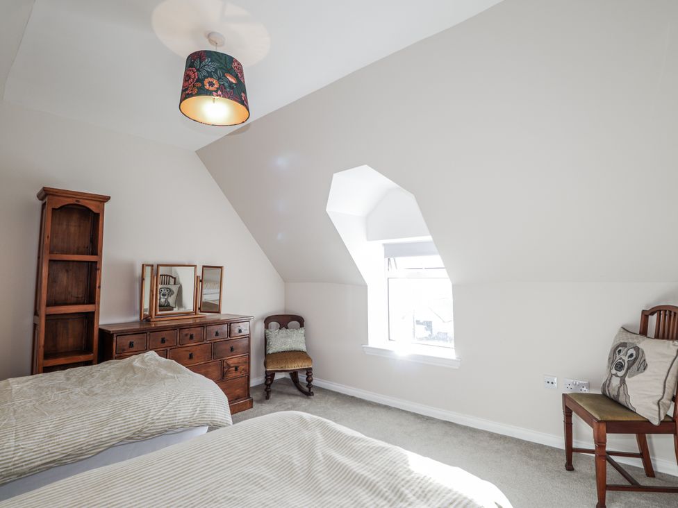 A bedroom with two beds and wooden furniture at 15 New Shawbost in Shawbost