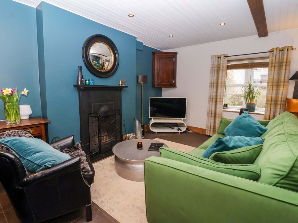 A living room with a green sofa, TV, and coffee table at The Green in Sawley near Ripon