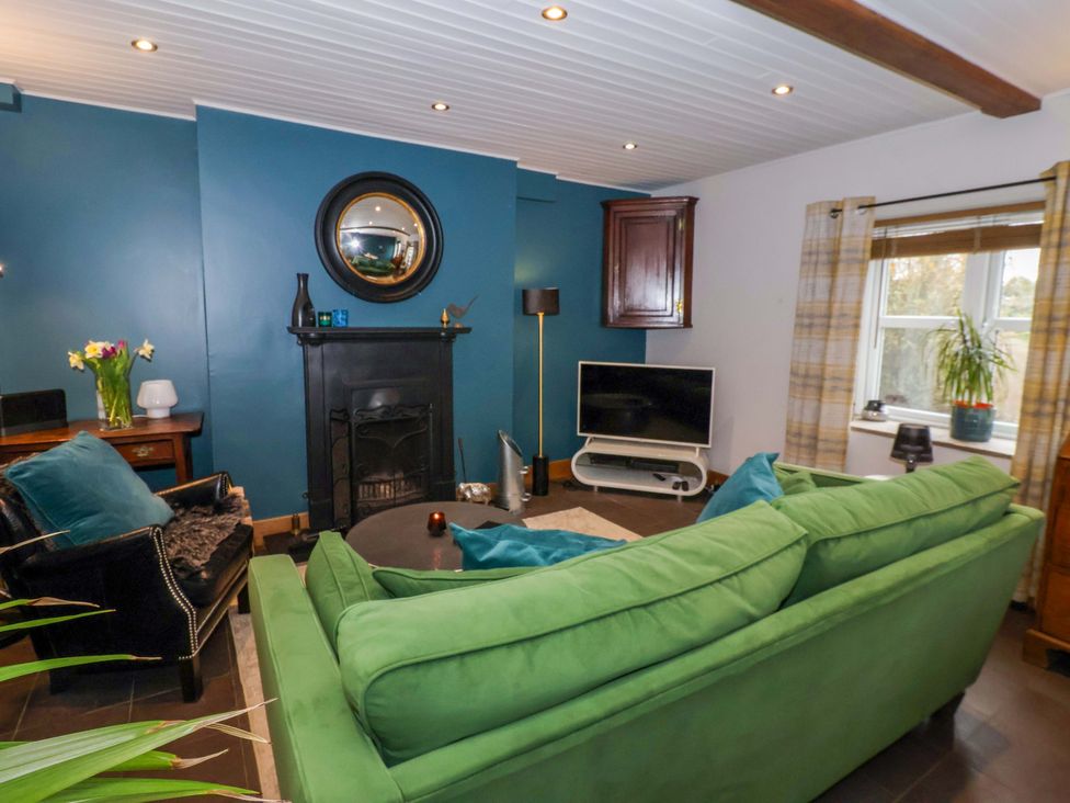 A living room with a green sofa and television at The Green in Sawley near Ripon