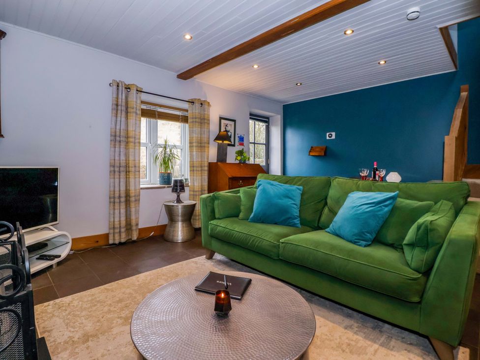 A living room with a green sofa and television at The Green in Sawley near Ripon
