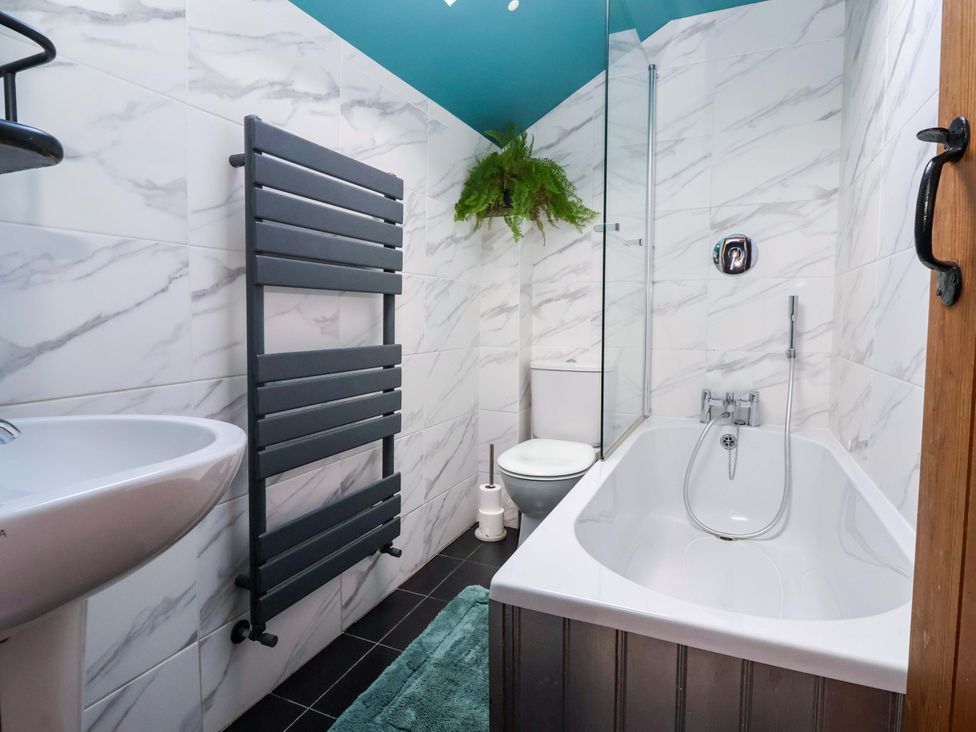 A bathroom with a bathtub, toilet, sink, and towel rail at The Green in Sawley near Ripon