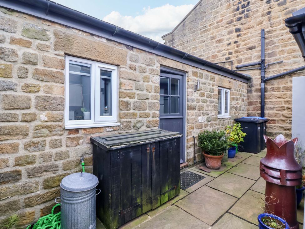 An outdoor area with a stone wall, door, windows, and storage items at The Green in Sawley near Ripon