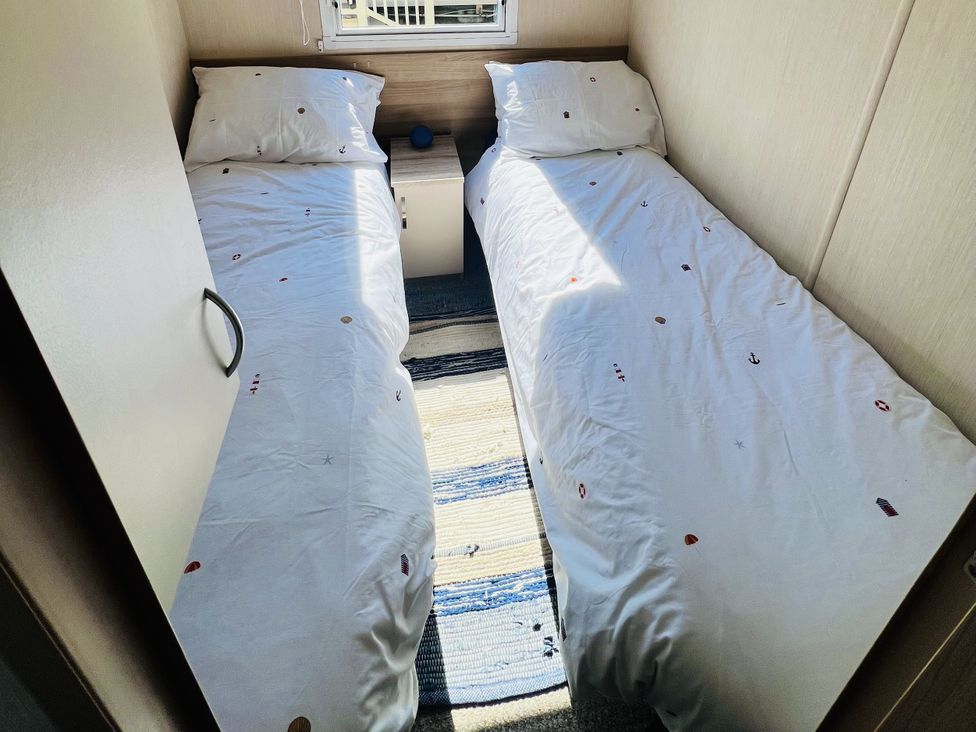 A bedroom with two beds and a nightstand at The Wild’s Waterside Haven in Cleethorpes