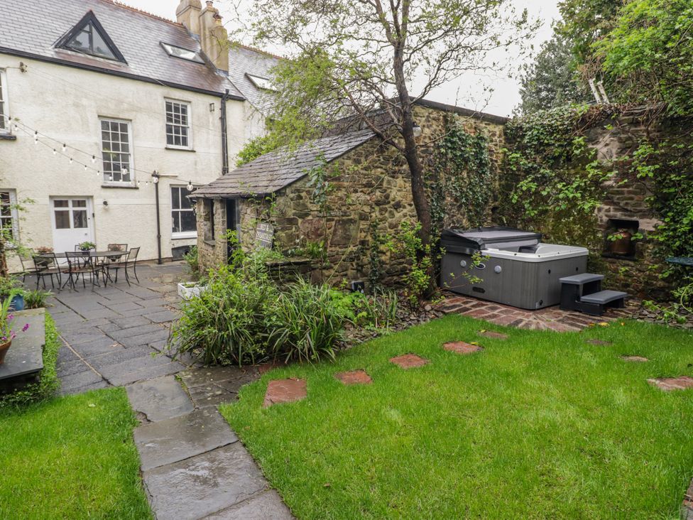 A garden with a hot tub and table with chairs at The Secret Garden in Narberth