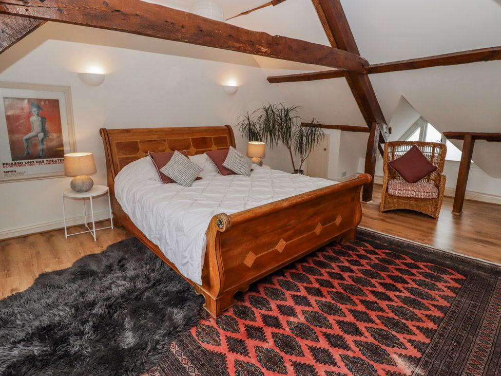 A bedroom with a wooden bed and decorative rug at The Secret Garden in Narberth