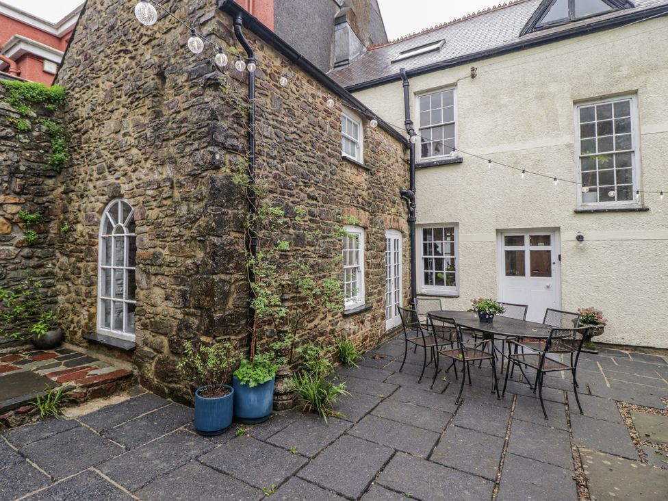 An outdoor area with a stone wall and a table with chairs at The Secret Garden in Narberth