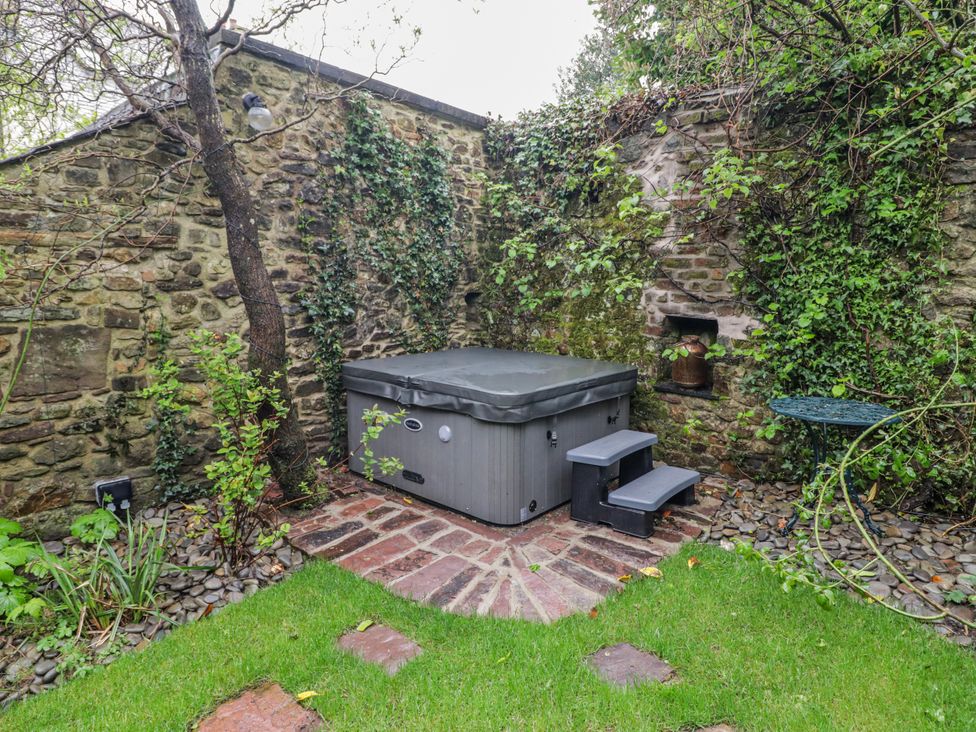 A garden with a hot tub and stone wall at The Secret Garden in Narberth