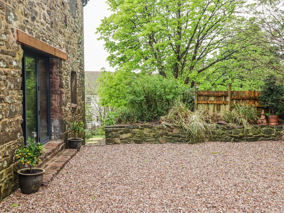 An outdoor space with gravel surface and stone wall at The Secret Garden in Narberth