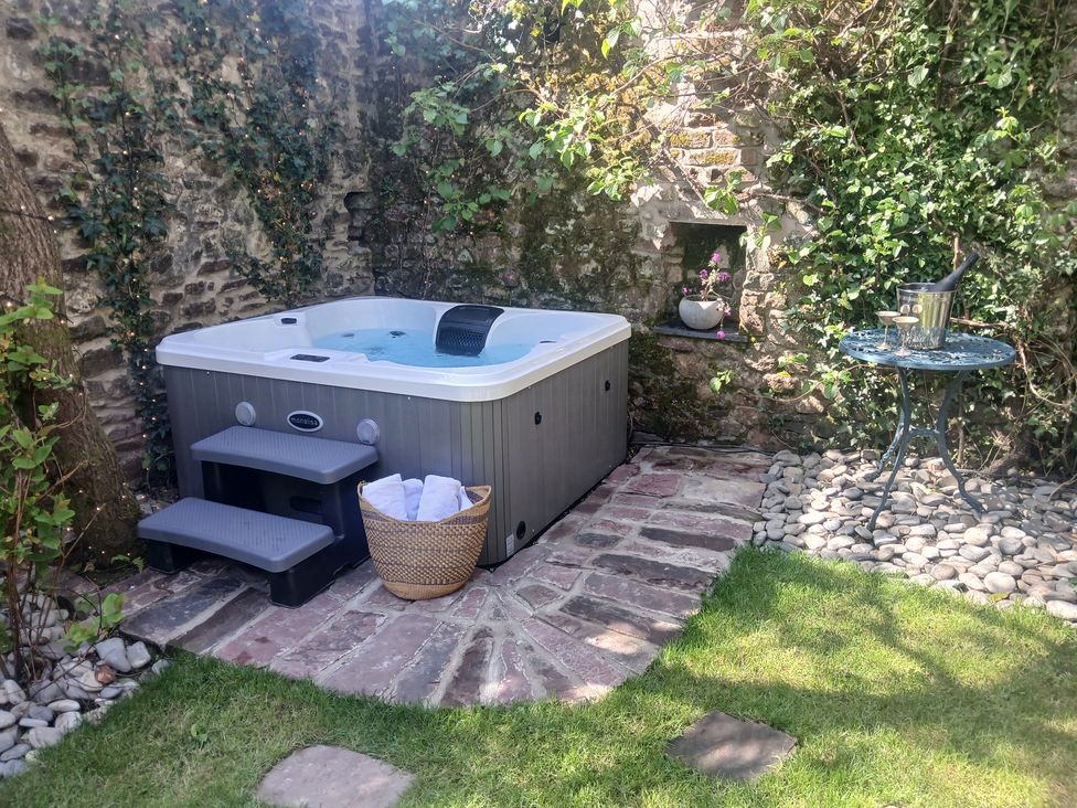 A garden with a hot tub and small table at The Secret Garden in Narberth