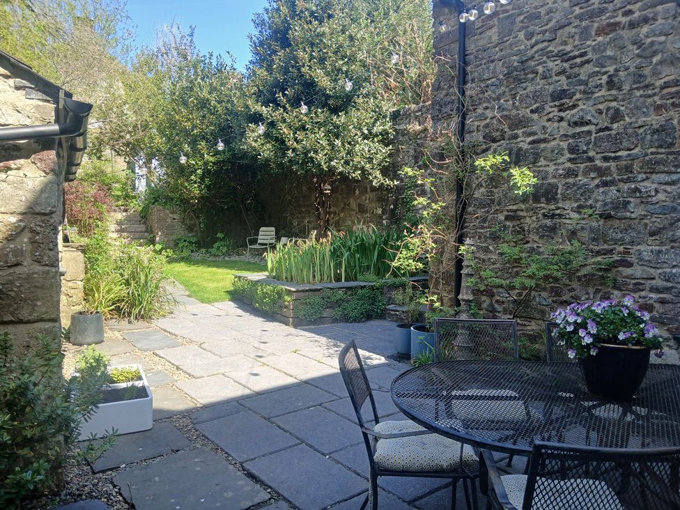 A garden with stone walls and a table with chairs at The Secret Garden in Narberth