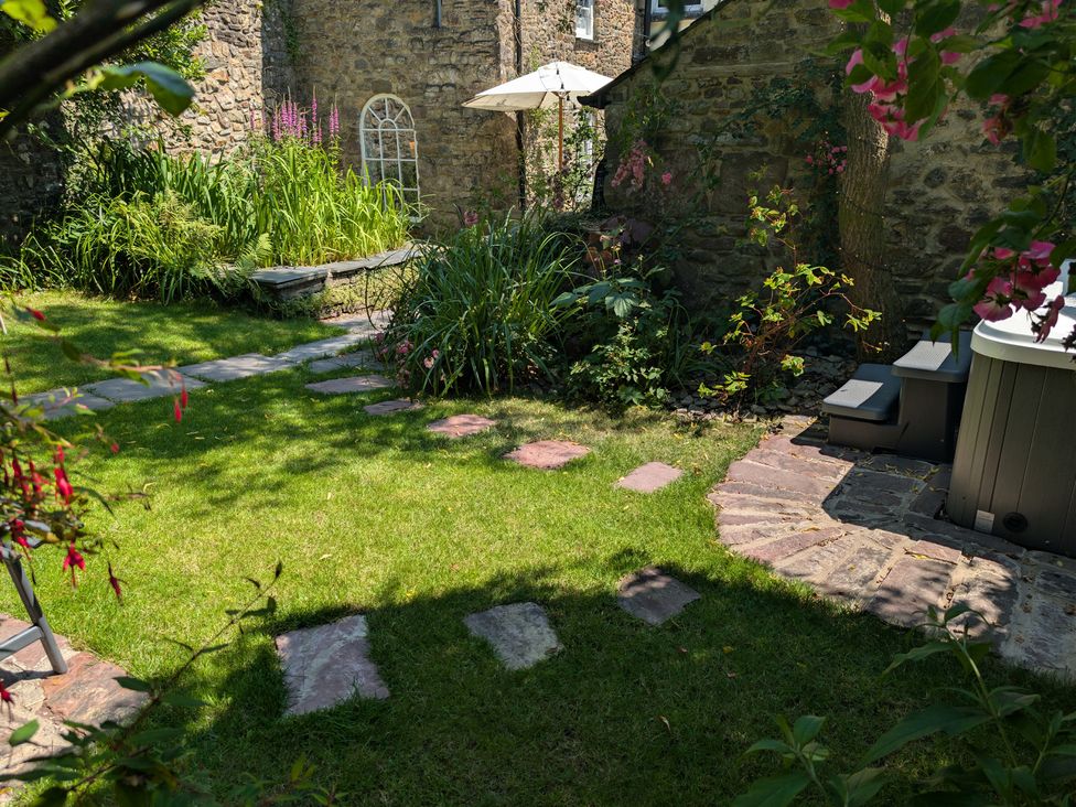 A garden with a pathway and hot tub at The Secret Garden in Narberth