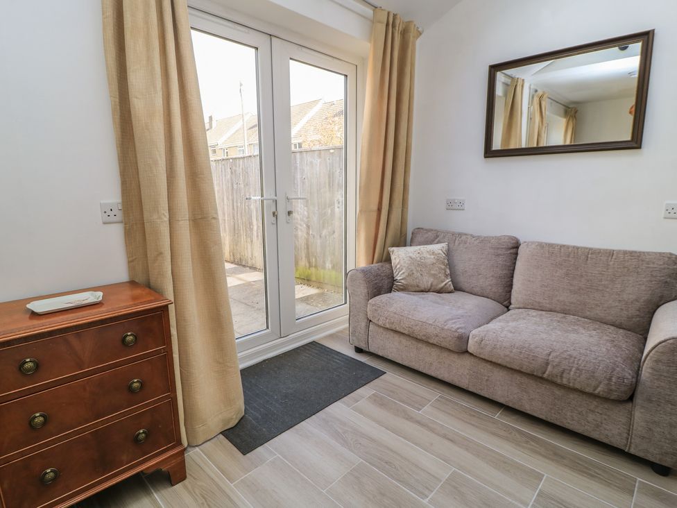 A snug with a sofa and a door leading outside at 11 Berry Close Painswick