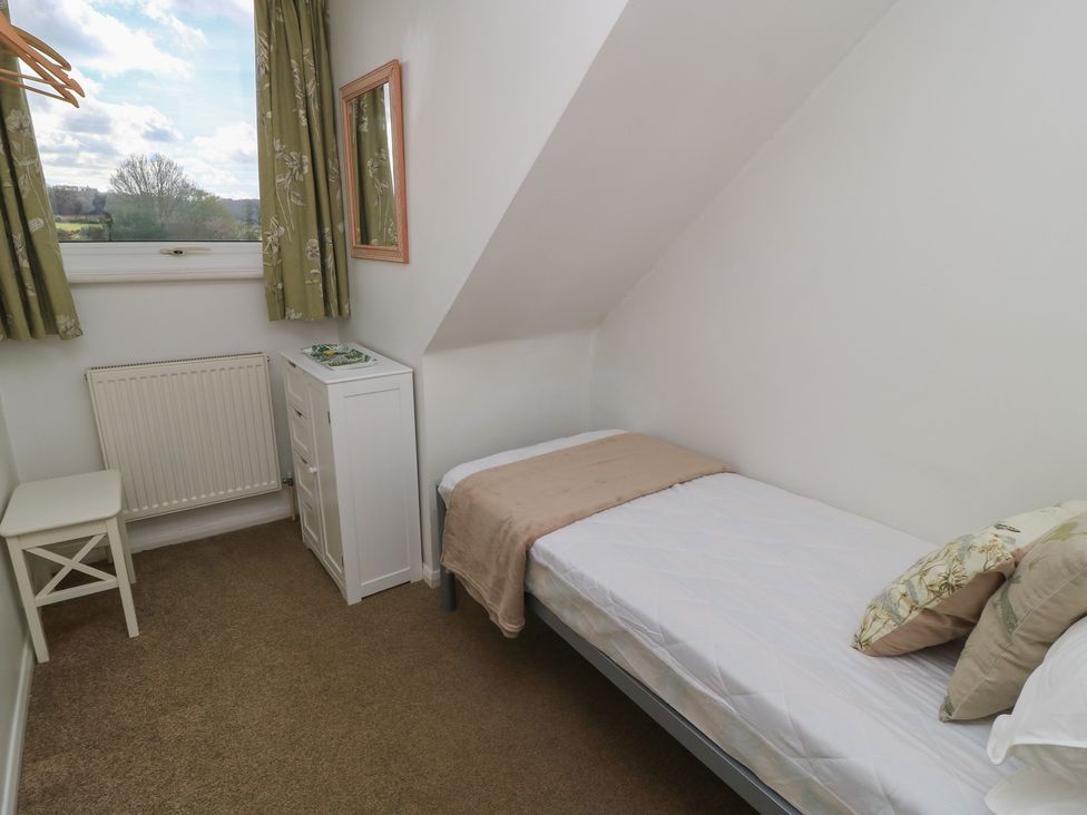 A bedroom with a bed and a chair at 11 Berry Close, Painswick
