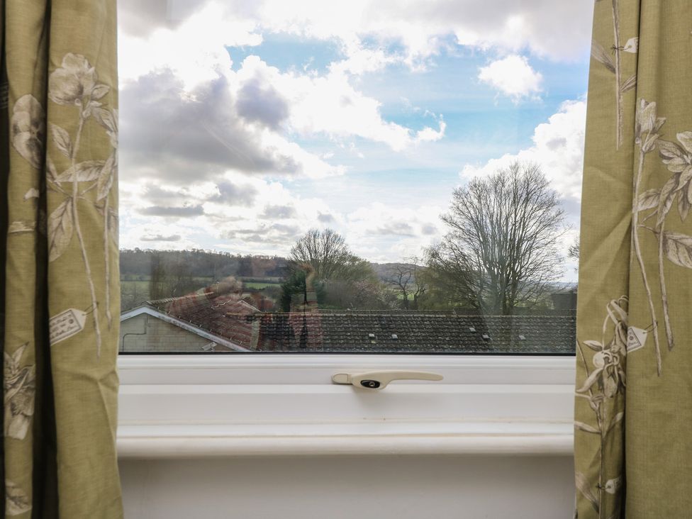 A window with curtains overlooking a landscape at 11 Berry Close in Painswick