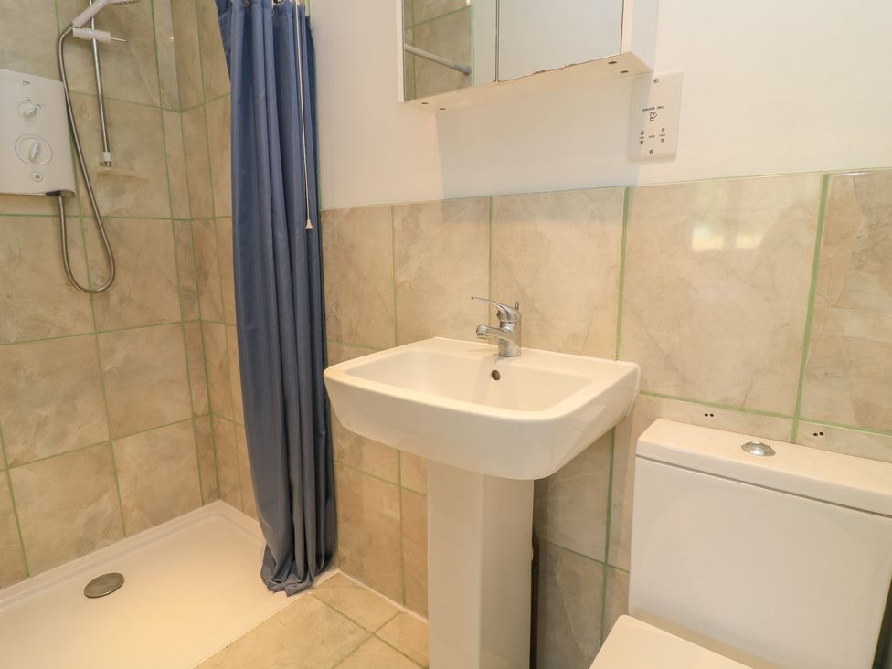A bathroom with a shower, sink, and toilet at 11 Berry Close in Painswick