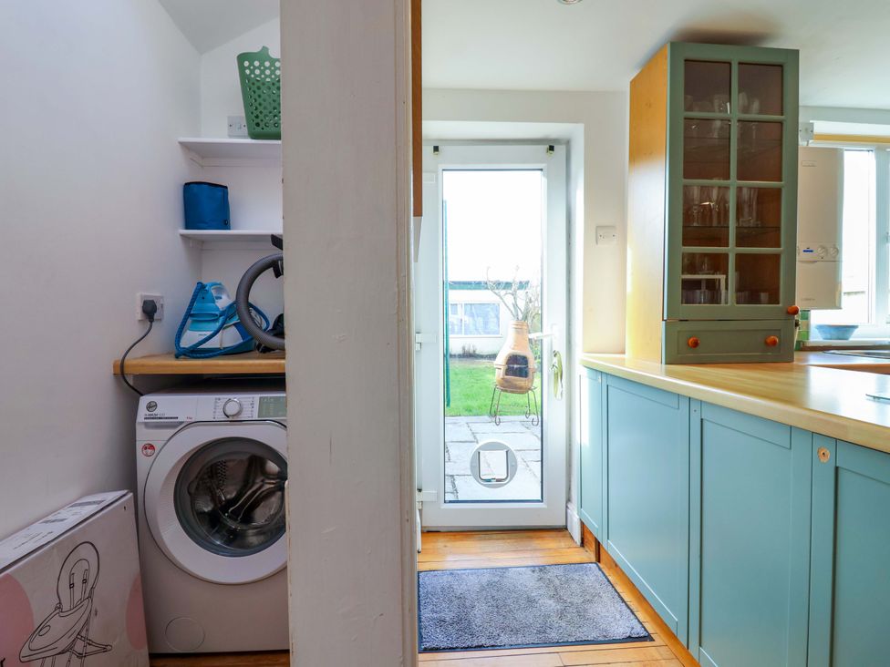 A laundry room with a washing machine and shelves at 12 Heathfield Terrace