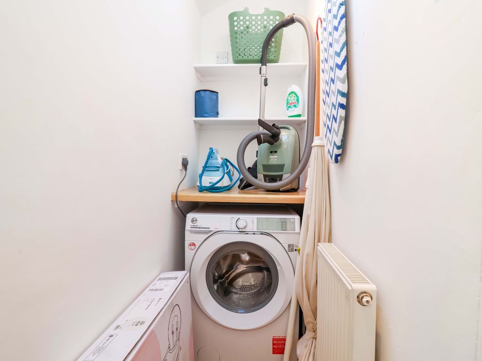 A laundry room with washing machine, vacuum cleaner and ironing board at 12 Heathfield Terrace