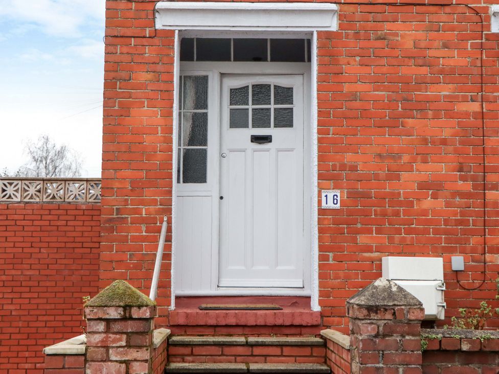 An entrance with a white door and brick wall at 16 Elmbank Gardens in Paignton