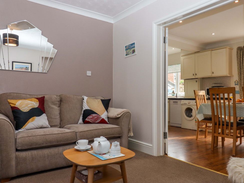 A living room with a sofa and coffee table leading to a kitchen at 16 Elmbank Gardens Paignton