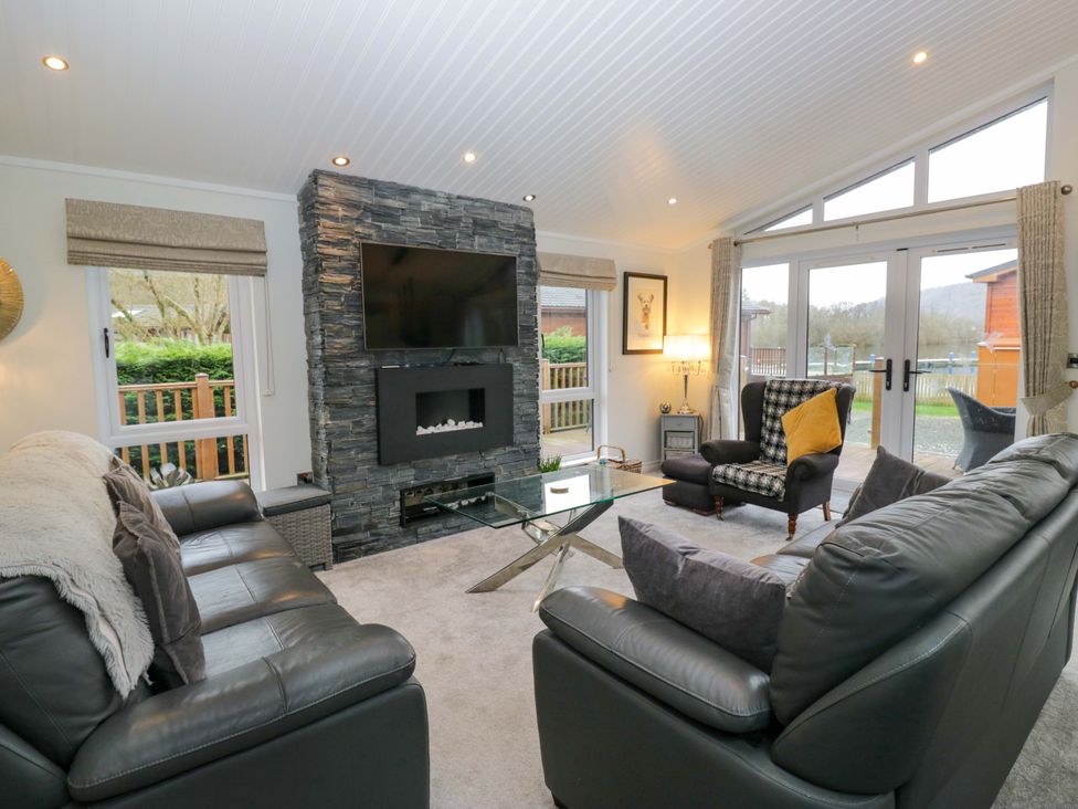 A living room with a television and fireplace at Waters Edge Lodge in Windermere