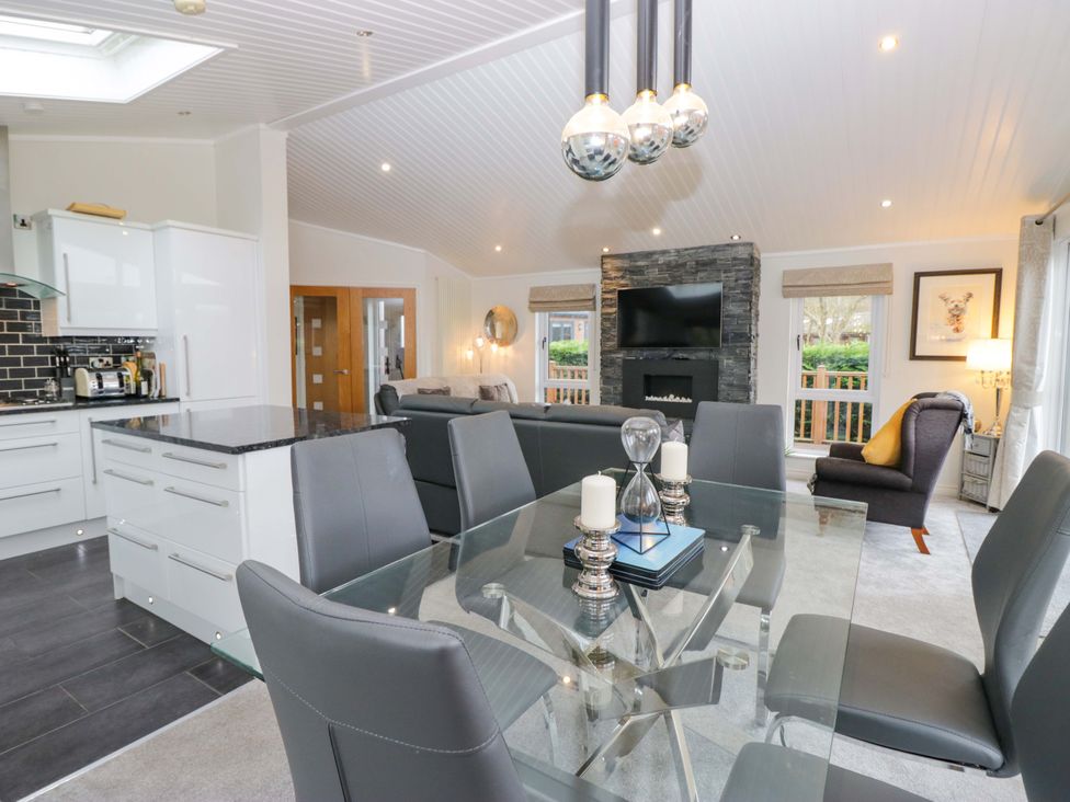 A dining area with a glass table and chairs at Waters Edge Lodge in Windermere