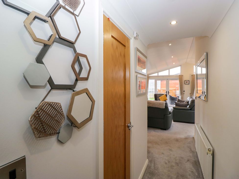 A hallway with wall mirrors and a door at Waters Edge Lodge in Windermere