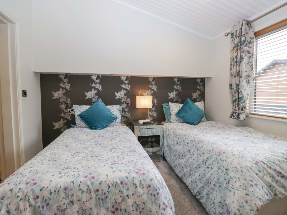 A bedroom with two single beds and a bedside table at Waters Edge Lodge in Windermere
