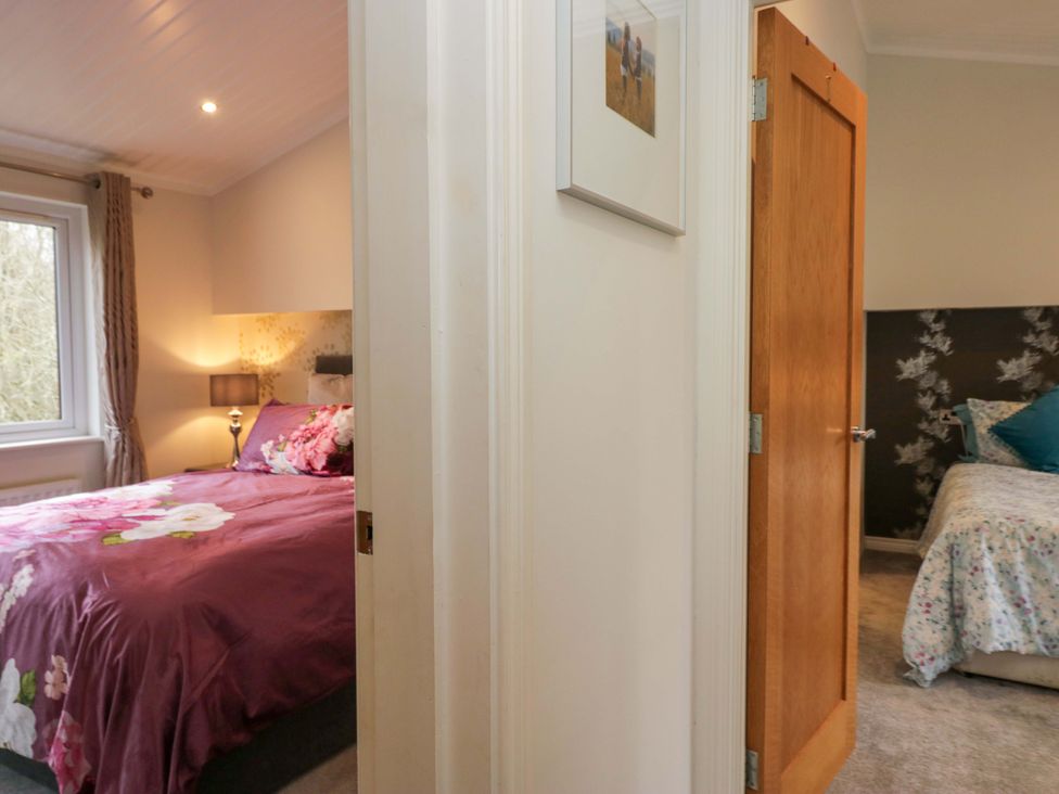 A bedroom with two beds and a window at Waters Edge Lodge in Windermere